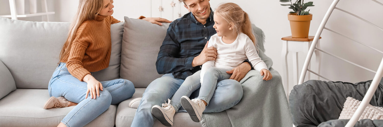 Vanhemmat ja lapsi istuvat sohvalla perheterapiassa