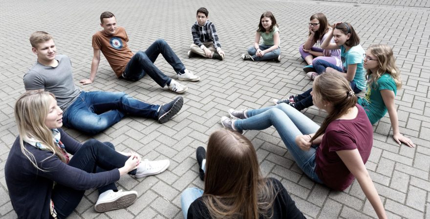 Nuorisoryhmä istuu ringissä pihalla